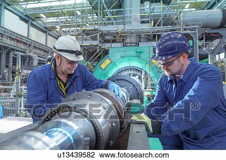 Stock Image - Engineers inspecting gears at generator end in nuclear power station during outage. Fotosearch