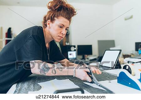 Picture - Fashion designer cutting fabric from dressmaker's pattern. Fotosearch