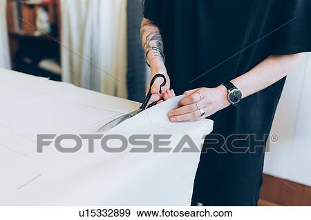 Stock Photo - Fashion designer cutting paper pattern. Fotosearch