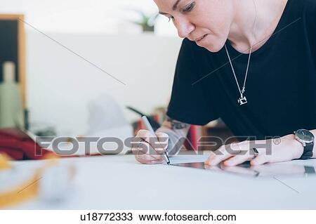 Stock Image - Fashion designer drawing and creating dressmaker's pattern. Fotosearch