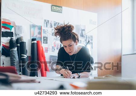 Stock Image - Fashion designer drawing and creating dressmaker's pattern. Fotosearch
