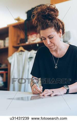 Stock Photo - Fashion designer drawing and creating dressmaker's pattern. Fotosearch