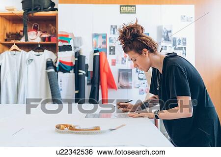 Stock Photograph - Fashion designer drawing and creating dressmaker's pattern. Fotosearch