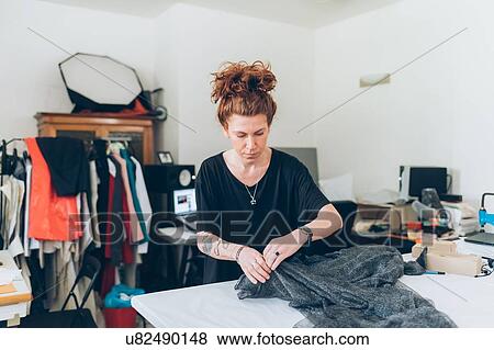 Stock Photo - Fashion designer laying out fabric on workbench. Fotosearch