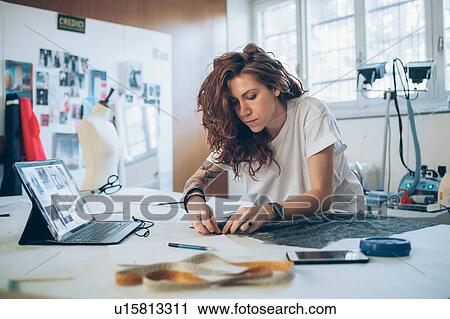 Stock Image - Fashion designer pinning fabric cutouts. Fotosearch
