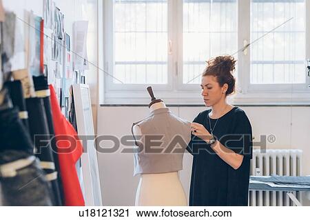 Stock Image - Fashion designer pinning garment onto dressmaker's dummy. Fotosearch