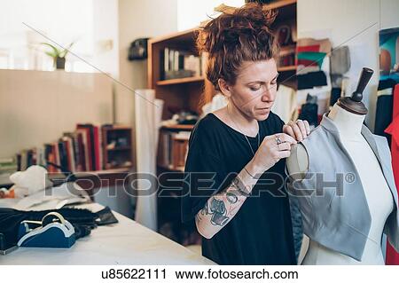 Stock Image - Fashion designer pinning garment onto dressmaker's dummy. Fotosearch
