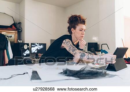 Stock Photo - Fashion designer researching using digital tablet. Fotosearch