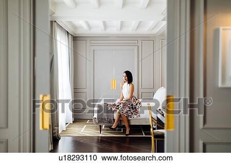 Stock Image - Fashionable woman beside window in suite. Fotosearch