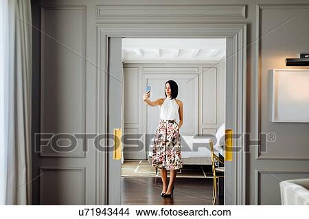 Picture - Fashionable woman taking selfie in suite. Fotosearch