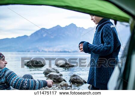 Stock Photo - Father and son camping on lakeside, view from inside tent, Onno, Lombardy, Italy. Fotosearch