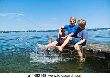 Stock Photo - Father and son cooling feet in water, Lake Starnberg, Bavaria, Germany. Fotosearch