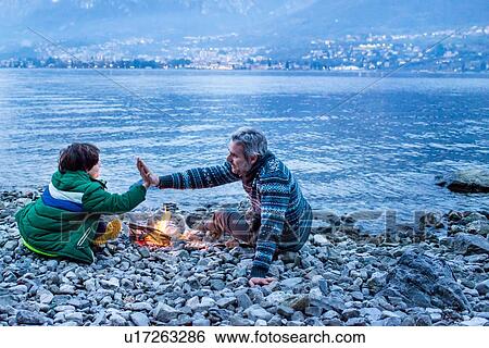 Father and son high fiving by campfire, Onno, Lombardy, Italy View Large Photo Image Stock Photograph - Father and son high fiving by campfire, Onno, Lombardy, Italy. Fotosearch