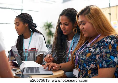 Stock Image - Female and male higher education students team working and using laptop in college classroom. Fotosearch