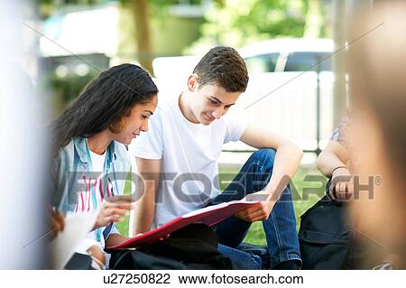 Female and male higher education students looking at paperwork on college campus lawn View Large Photo Image Stock Image - Female and male higher education students looking at paperwork on college campus lawn. Fotosearch