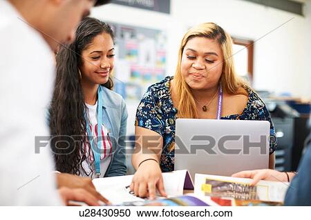 Stock Image - Female and male higher education students team working and using laptop in college classroom. Fotosearch