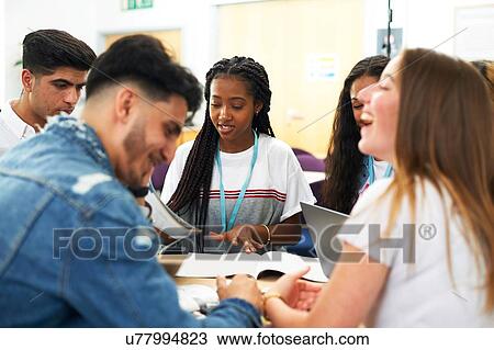Stock Image - Female and male higher education students discussing project in college classroom. Fotosearch