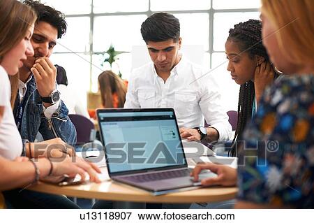 Stock Photo - Female and male higher education students team working and using laptop in college classroom. Fotosearch