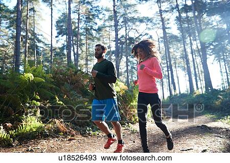 Female and male runners running together in sunlit forest View Large Photo Image Stock Image - Female and male runners running together in sunlit forest. Fotosearch