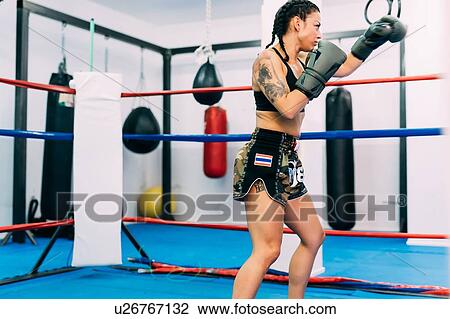 Stock Image - Female boxer practising in boxing ring. Fotosearch