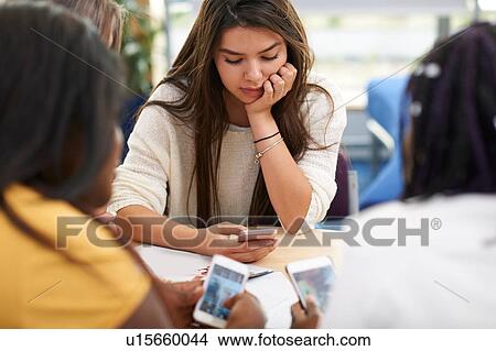 Female higher education students looking at smartphones in college classroom View Large Photo Image Picture - Female higher education students looking at smartphones in college classroom. Fotosearch