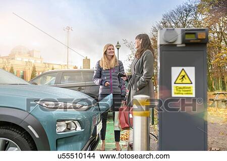 Picture - Female shoppers charging electric car at charge point, Manchester, UK. Fotosearch