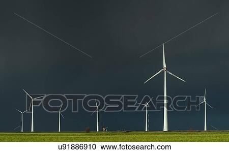 Stock Image - Field landscape with dramatic sky behind wind farm and traditional windmill in north Netherlands, near waddensea dyke. Fotosearch