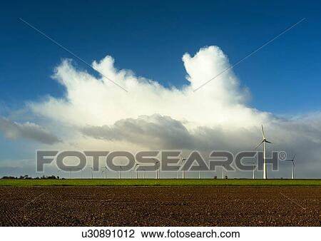 Stock Image - Field landscape with huge rainclouds over modern wind farm in north of Netherlands. Fotosearch
