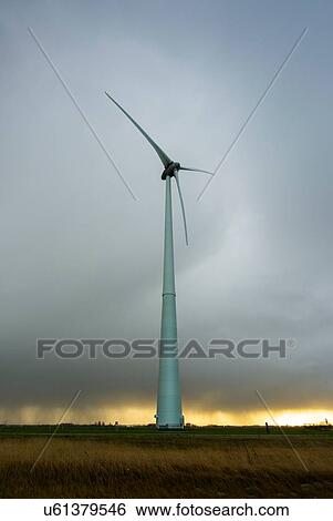 Stock Photograph - Field landscape with storm clouds and wind turbine on wind farm in north Netherlands, near waddensea dyke. Fotosearch
