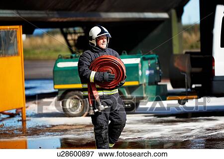 Stock Photo - Fireman carrying fire hose reel, Darlington, UK. Fotosearch