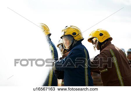 Firemen covered by water spray from fire hose View Large Photo Image Stock Image - Firemen covered by water spray from fire hose. Fotosearch
