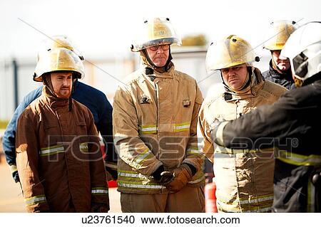 Stock Image - Firemen training, firemen listening to supervisor at training facility. Fotosearch