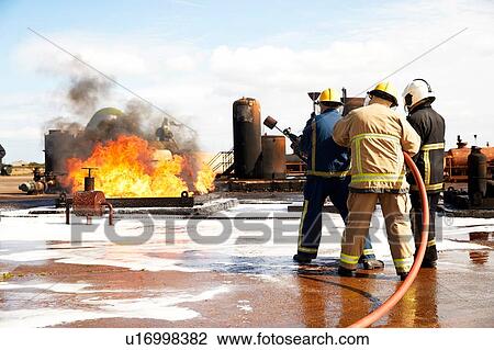Stock Image - Firemen training, firemen preparing to put out oil storage tank fire at training facility. Fotosearch
