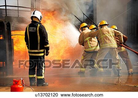 Firemen training, firemen spraying water at fire at training facility, rear view View Large Photo Image Stock Image - Firemen training, firemen spraying water at fire at training facility, rear view. Fotosearch
