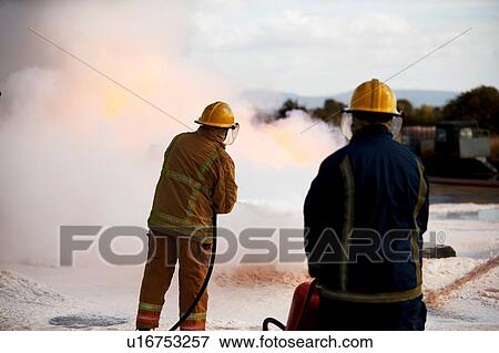 Stock Photo - Firemen training, firemen spraying firefighting foam at training facility. Fotosearch