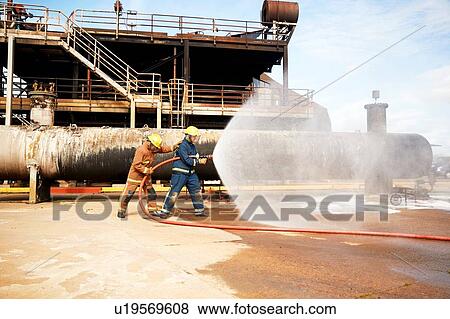 Firemen training, firemen spraying water from fire hose at training facility View Large Photo Image Stock Photo - Firemen training, firemen spraying water from fire hose at training facility. Fotosearch