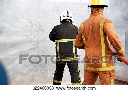 Firemen training, firemen spraying water at training facility, rear view View Large Photo Image Stock Photo - Firemen training, firemen spraying water at training facility, rear view. Fotosearch