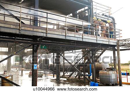 Stock Photograph - Firemen training, on training facility building spraying water. Fotosearch