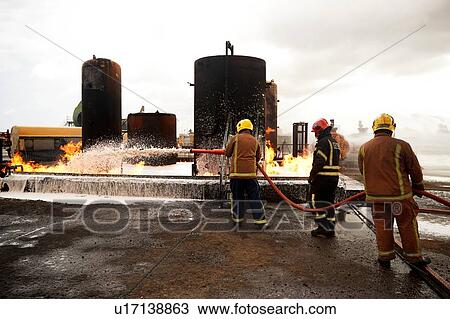 Firemen training, spraying firefighting foam onto oil storage tank fire at training facility View Large Photo Image Stock Image - Firemen training, spraying firefighting foam onto oil storage tank fire at training facility. Fotosearch