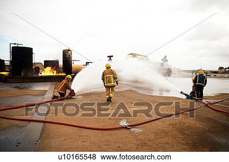Firemen training, spraying water onto fire at training facility View Large Photo Image Stock Photo - Firemen training, spraying water onto fire at training facility. Fotosearch