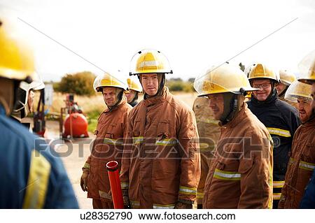 Stock Image - Firemen training, team of firemen listening at meeting at training facility. Fotosearch