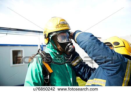 Stock Image - Firemen training to put on fire helmet, Darlington, UK. Fotosearch