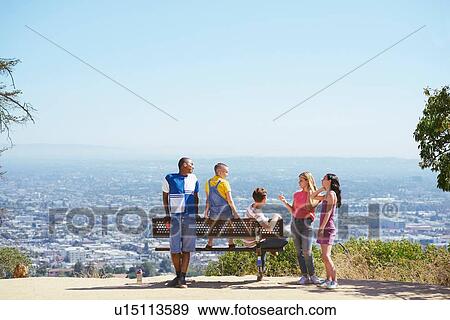 Stock Photo - Five young adult friends on cityscape hilltop bench, rear view, Los Angeles, California, USA. Fotosearch