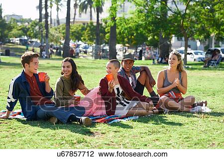 Stock Image - Five young adult friends sitting in park, Los Angeles, California, USA. Fotosearch