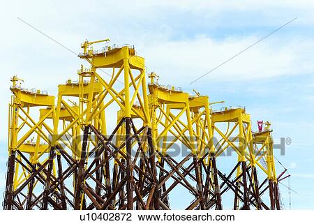 Stock Image - Foundations for offshore wind turbines stored Vlissingen harbour; these platforms are called jacket. waiting to be shipped to new north sea Borssele wind farm, Netherlands. Fotosearch