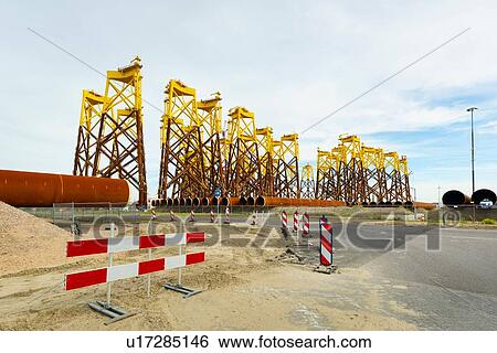 Stock Photograph - Foundations for offshore wind turbines stored Vlissingen harbour; these platforms are called jacket. waiting to be shipped to new north sea Borssele wind farm, Netherlands. Fotosearch