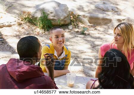Four young adult friends chatting at park picnic table, Los Angeles, California, USA View Large Photo Image Stock Photo - Four young adult friends chatting at park picnic table, Los Angeles, California, USA. Fotosearch