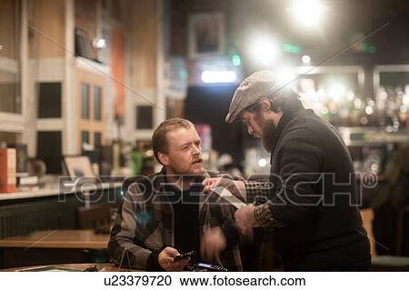 Stock Image - Friends paying bill at pub. Fotosearch