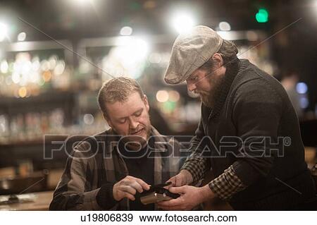 Stock Photo - Friends paying bill at pub. Fotosearch
