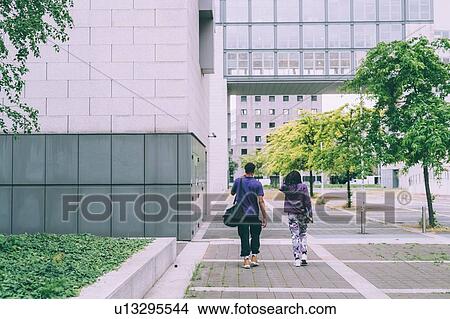Friends walking in building complex, Milan, Italy View Large Photo Image Picture - Friends walking in building complex, Milan, Italy. Fotosearch